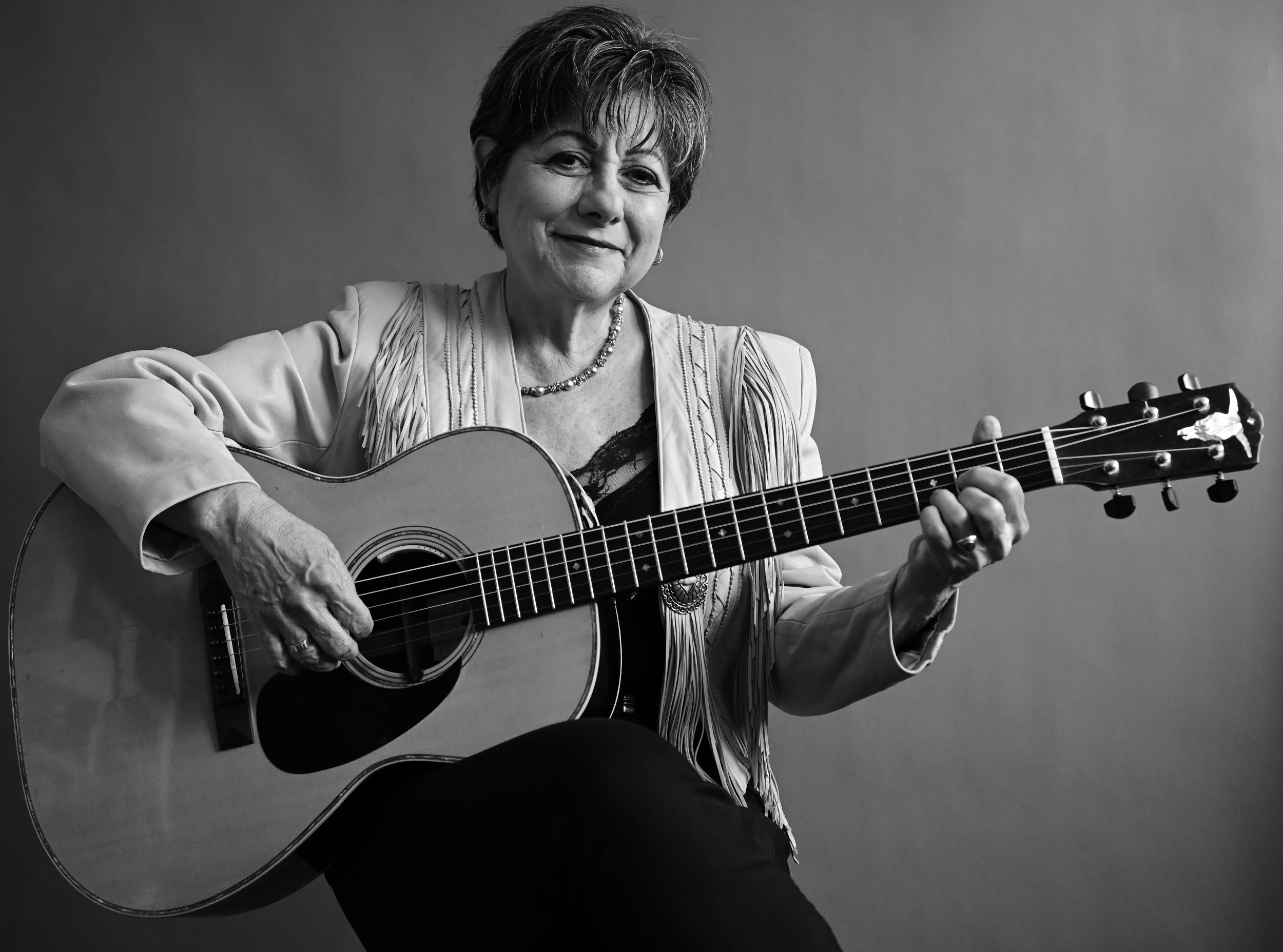 Tish Hinojosa with guitar, smiling.