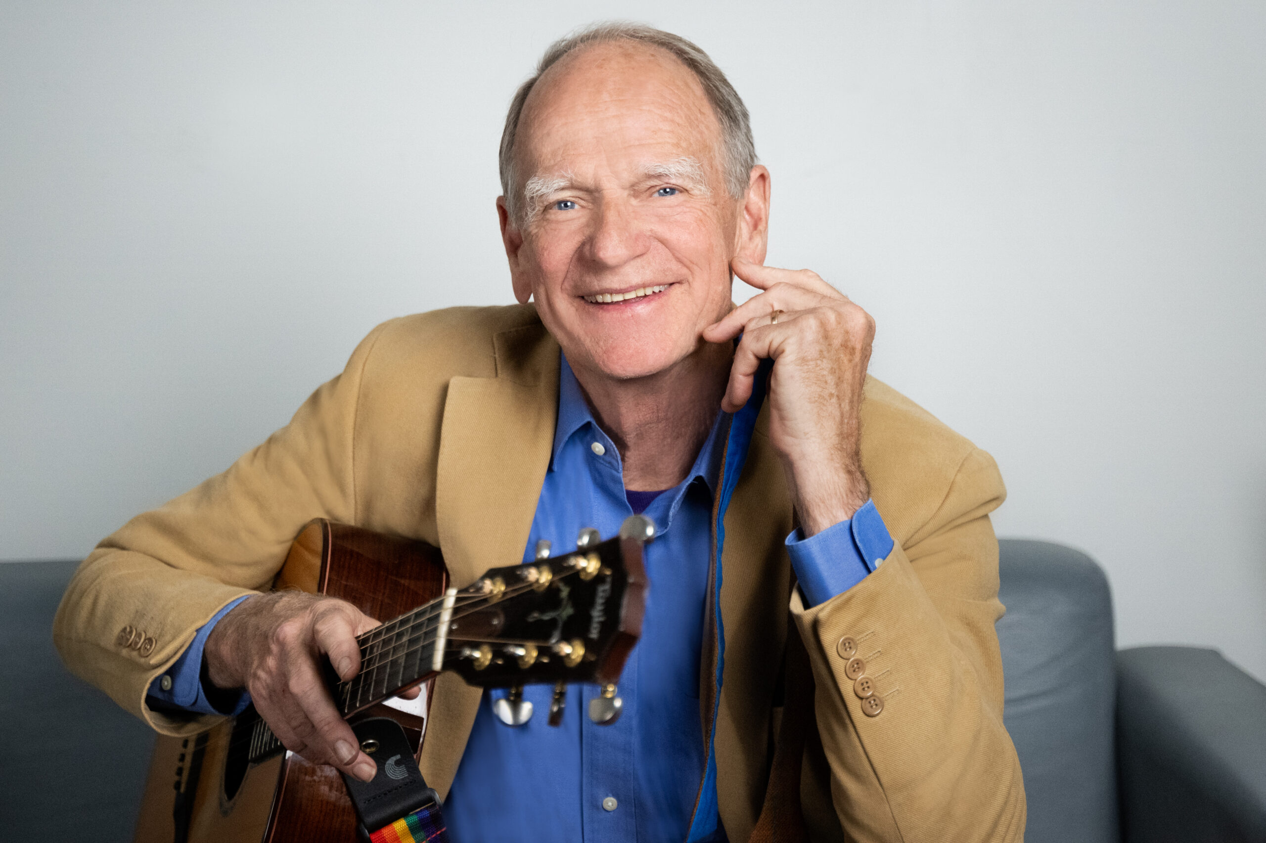 Livingston Taylor press photo. Holding guitar, smiling.
